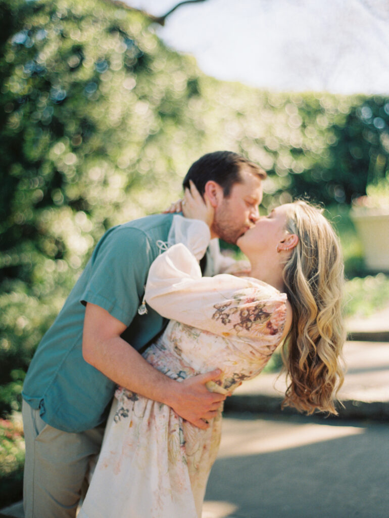 couple kissing in Texas garden for their engagement session Dreamy Outdoor Engagement Photos in Botanical Gardens