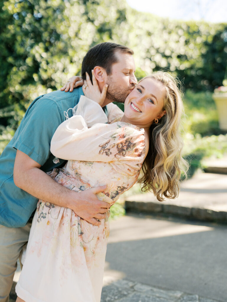 couple candidly smiling and kissing during texas garden engagement session 