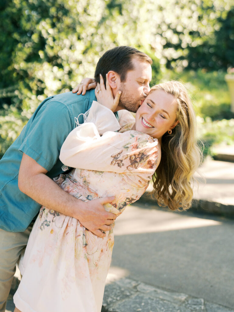 man kissing woman in garden engagement session 