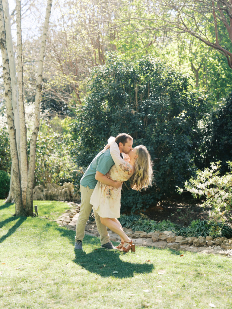man and woman kissing during garden engagement session Dreamy Outdoor Engagement Photos in Botanical Gardens