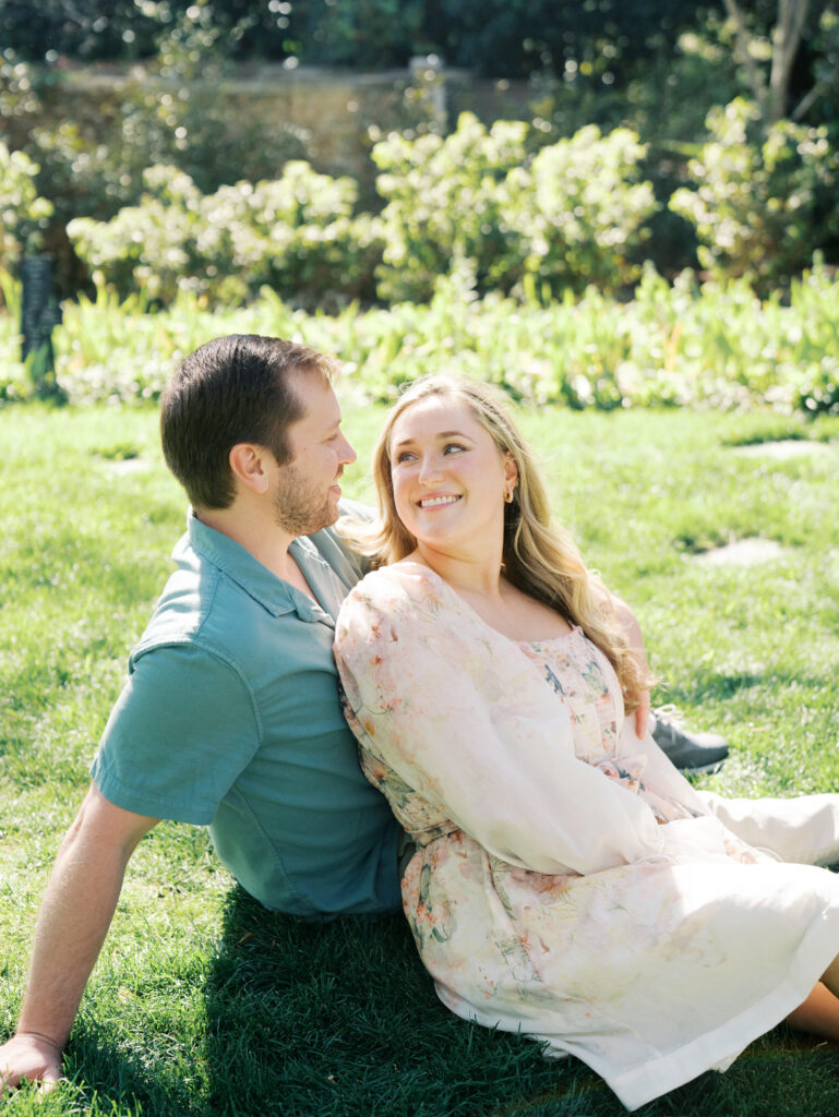 man and woman smiling at each other during a garden engagement session
