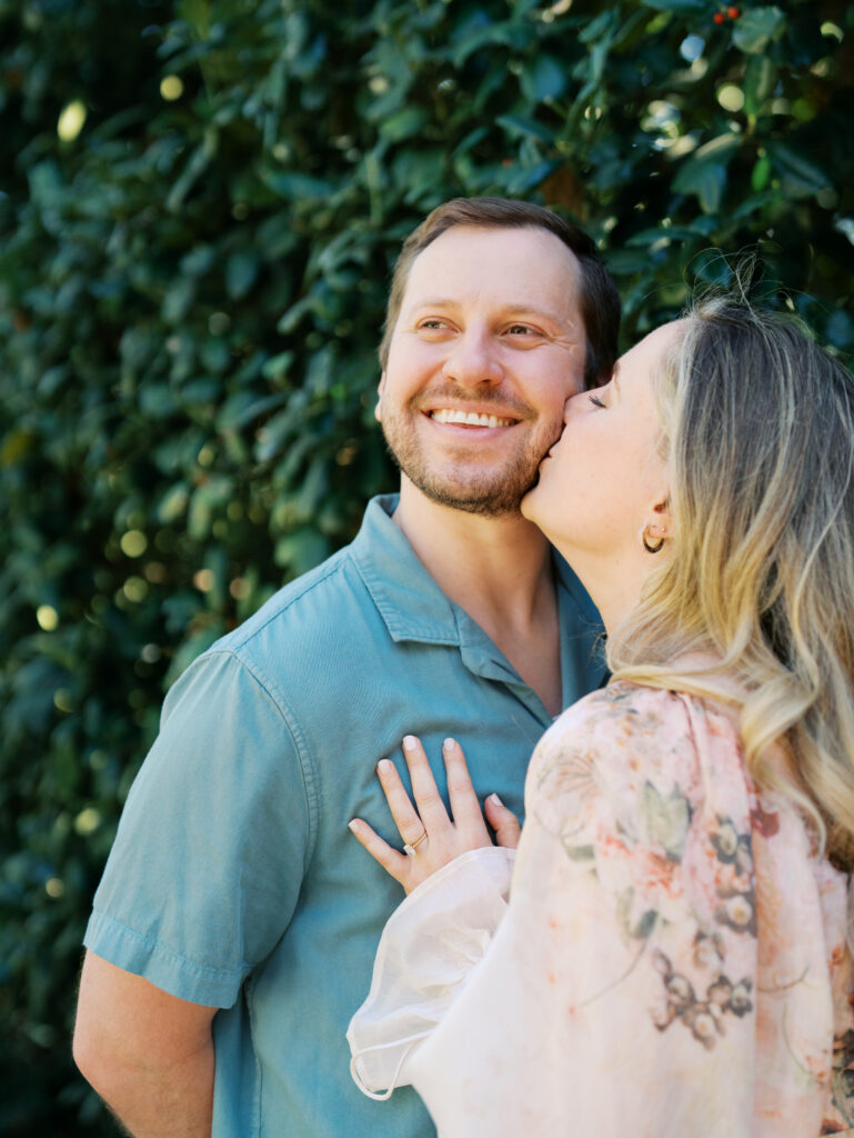 man kissing woman while smiling during Texas engagement session Dreamy Outdoor Engagement Photos in Botanical Gardens