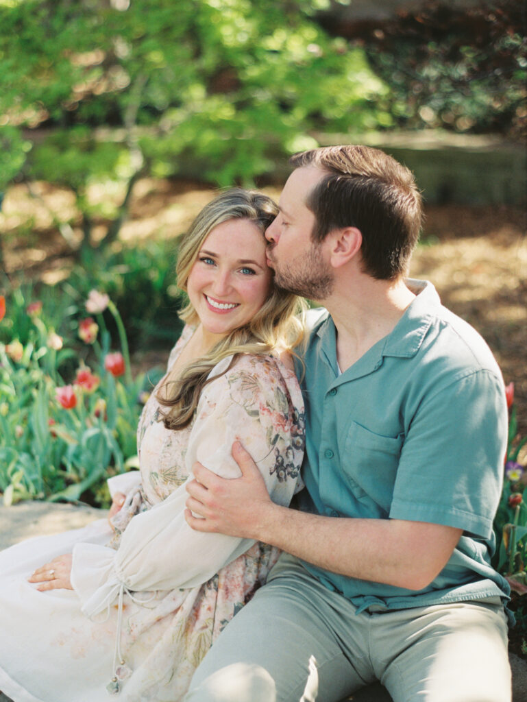 man kissing woman while smiling during Texas engagement session Dreamy Outdoor Engagement Photos in Botanical Gardens