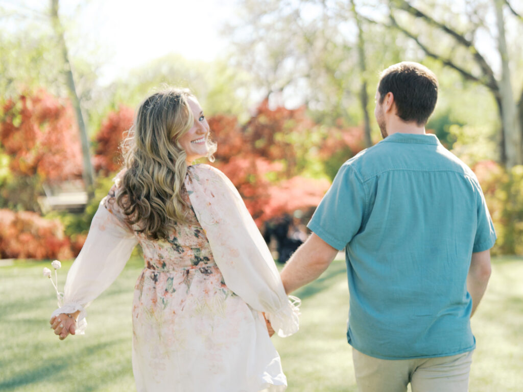 couple holding hands walking surrounded by gardens and greenery