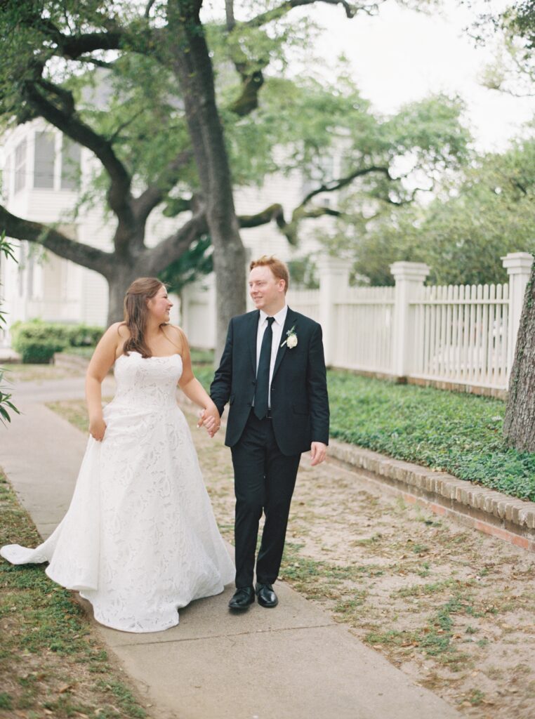 bride and groom smiling and holding hands on wedding day 