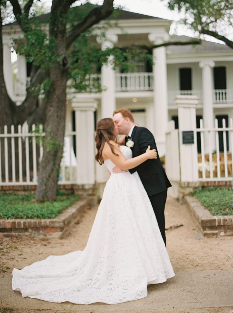 bride and groom kissing on wedding day in front of venue in gelveston 