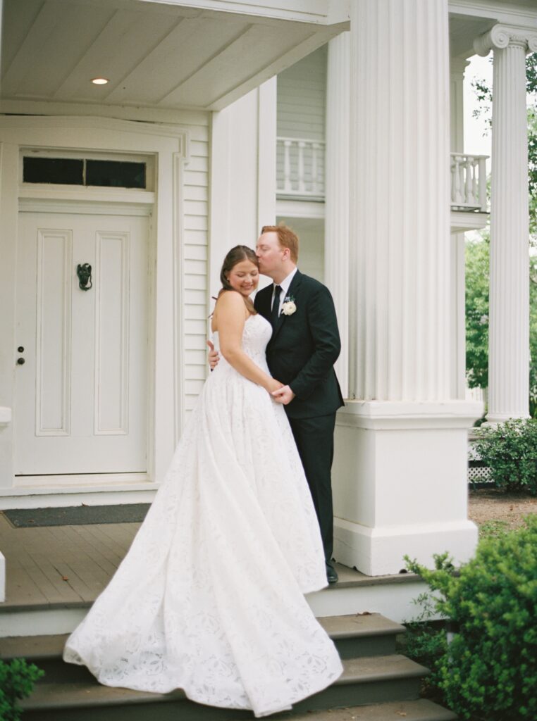 groom kissing brides cheek and smiling on wedding day 