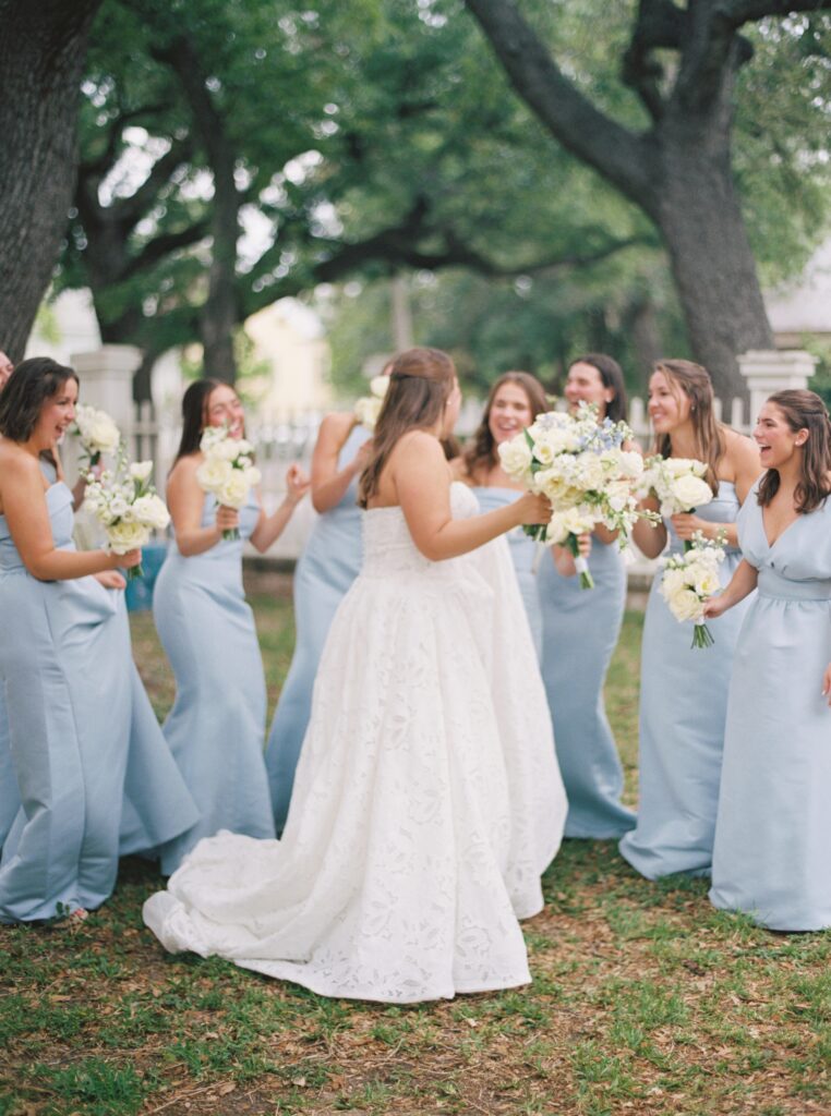 bride and her bridesmaids holding flowers and smiling 