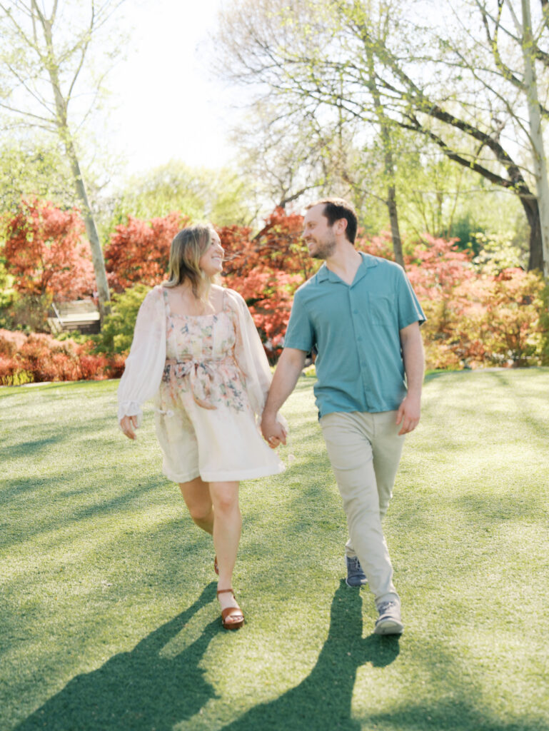 couple holding hands and walking through botanical gardens for outdoor engagement photos