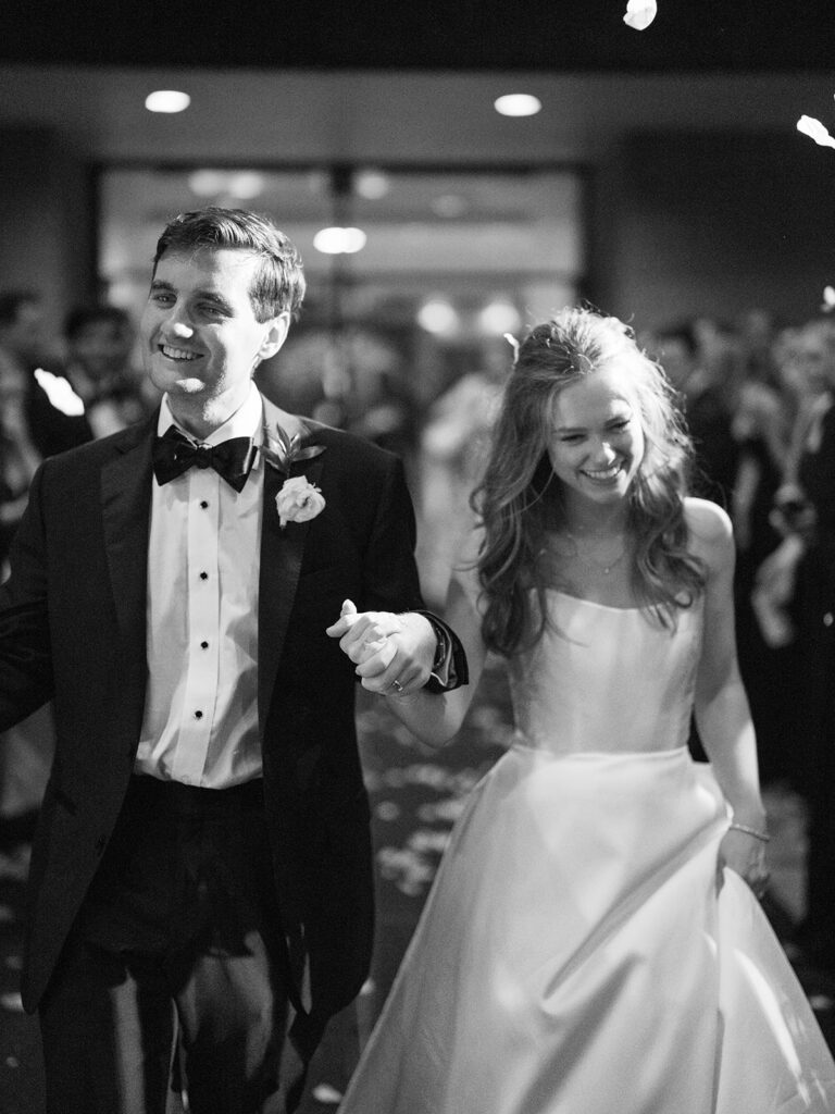 A smiling couple in formal attire dances together at a crowded event, surrounded by other people also dancing for a Houstonian Hotel Wedding