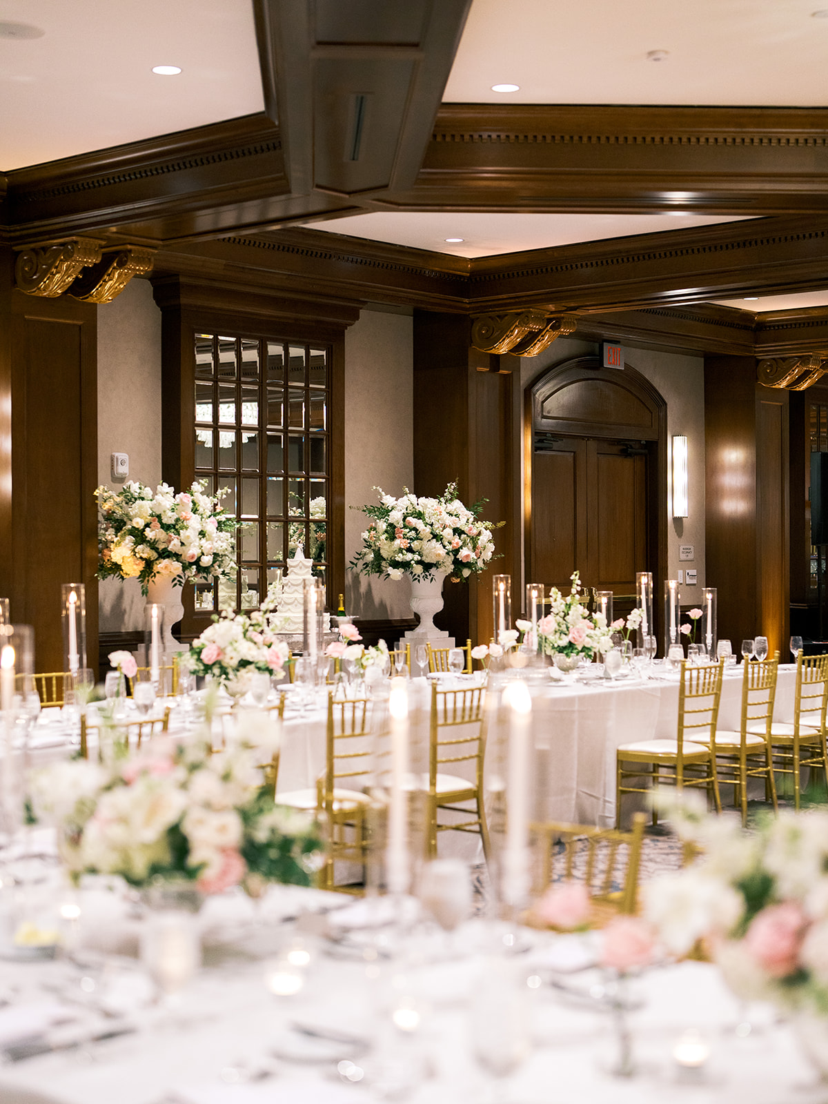 Elegant banquet hall set for an event with long tables, gold chairs, tall floral centerpieces, and candlelight decorations for a Houstonian Hotel Wedding